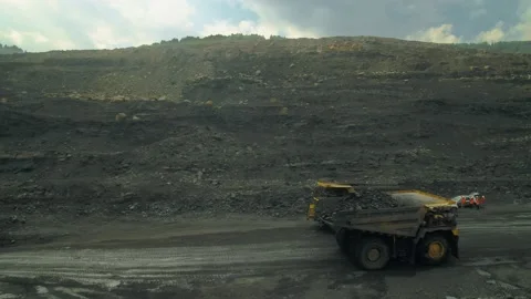 Two giant dump trucks are transporting coal in a quarry Stock Footage 145290396