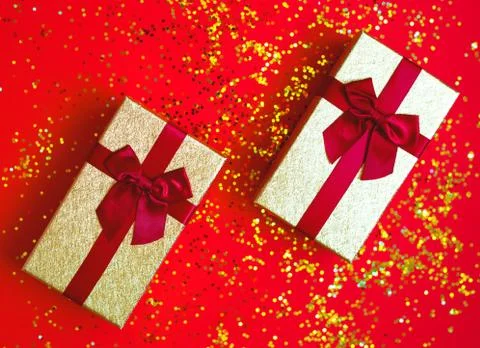 Two gift box with bowes on red-gold background Stock Photos