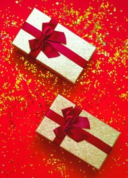 Two gift box with bowes on red-gold background Stock Photos