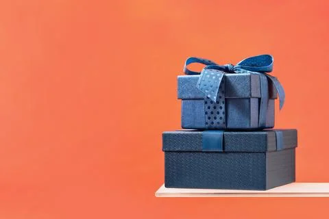 Two gift boxes with a blue bow on coral background Stock Photos