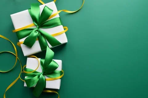 Two gift boxes with green satin ribbon bows on a green background Stock Photos