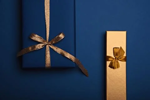 Two gift boxes wrapped in classic blue and golden paper with a gold ribbon. Stock Photos
