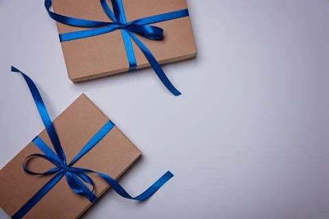 Two gift boxes wrapped in craft paper with a classic blue ribbons. Stock Photos