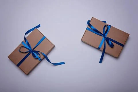 Two gift boxes wrapped in craft paper with a classic blue ribbons. Fotos de archivo