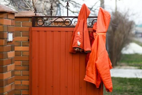 Two ginger red jackets hanging on the fence, child and grown up Stock Photos