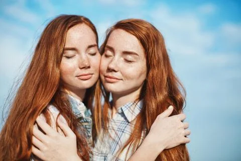 Two ginger sisters hugging each other on a bright sunny day sharing their warmth Stock Photos