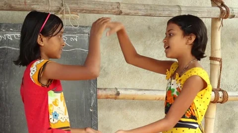 Two girl students play a fun clapping game in front of a chalk board Stock Footage 65803201