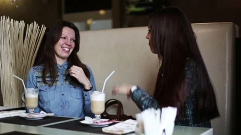 Two girlfriends in a cafe drinking coffee, talking and laughing. Stock Footage 72166098