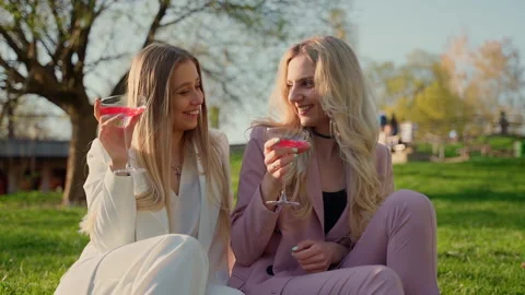 Two girlfriends drinking red champagne in park outdoors Stock Footage 194297400
