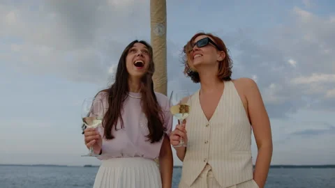 Two girlfriends in a good mood drink wine while walking on a yacht Stock Footage 201191652