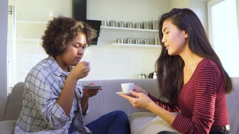 Two girlfriends gossiping while sitting on the couch Stock Footage 171235867