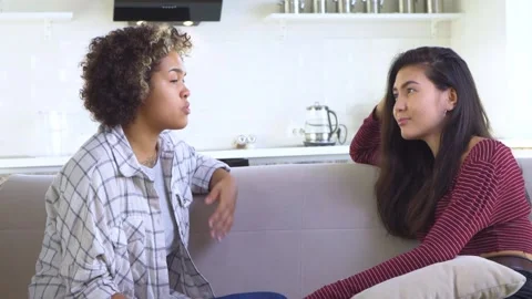 Two girlfriends gossiping while sitting on the couch Stock Footage 172298645