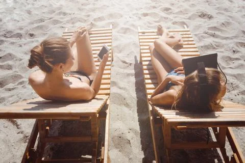 Two girlfriends having fun with VR glasses and smartphone on beach Stock Photos