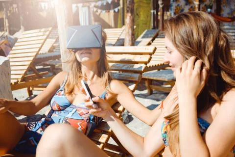 Two girlfriends having fun with VR glasses and smartphone on beach Stock Photos