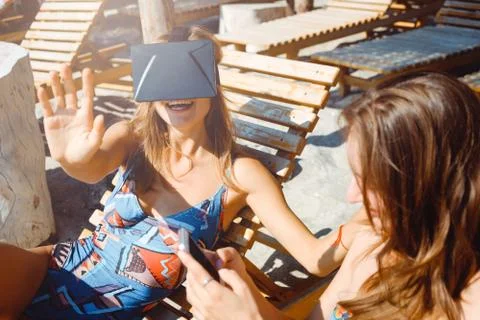 Two girlfriends having fun with VR glasses and smartphone on beach Stock Photos
