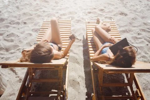 Two girlfriends having fun with VR glasses and smartphone on beach Stock Photos