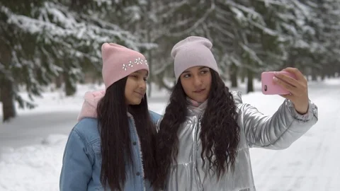 Two girlfriends make selfie using a smartphone while standing in a winter forest Stock Footage 98528016