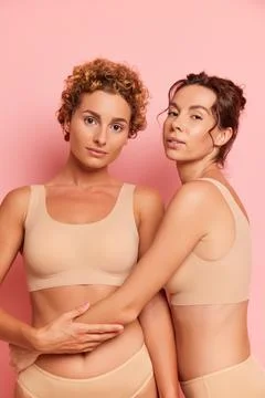 Two girlfriends posing inside the studio, curly one standing full face, her Stock-Fotos