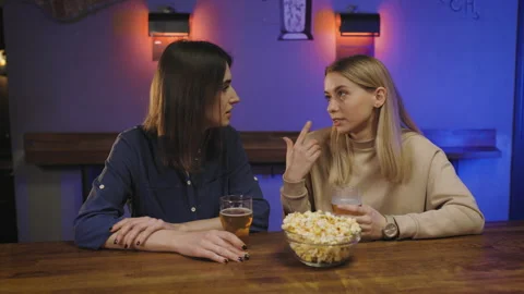 Two girlfriends in pub at bar counter drink beer and talking with each other. Stock Footage 147659781
