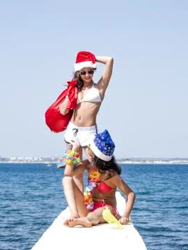 Two girlfriends in santa hat during beach vacation Stock Photos