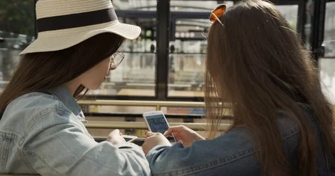 Two girlfriends sitting on a bench and talking. Two attractive girls are having Stock Footage 129847005