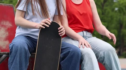 Two girlfriends sitting on a ramp and holding a wooden skateboard Vidéo 336657546