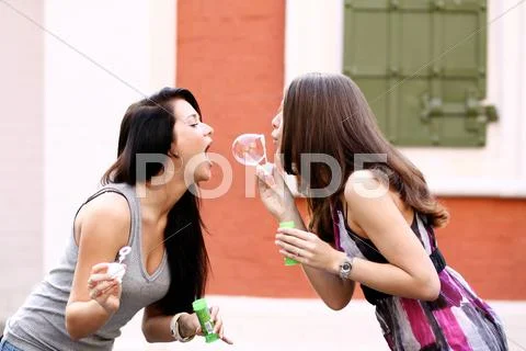Two girlfriends with soap bubbles outdoors Stock Photos
