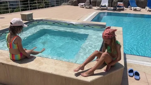 Two girlfriends in swimsuits sitting by the pool in the summer Stock Footage 241209179