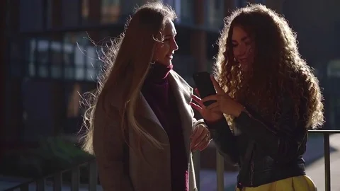 Two girlfriends talking and laughing watching fun stuff on smartphone outdoor in Video stock 97369142