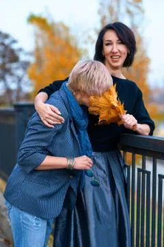 Two girlfriends talking and posing in autumn city park. Beautiful adult woman Stock Photos