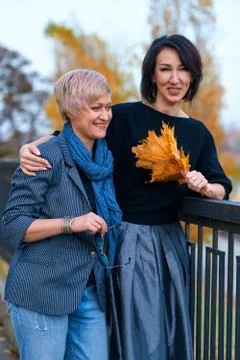 Two girlfriends talking and posing in autumn city park. Beautiful adult woman Stock Photos