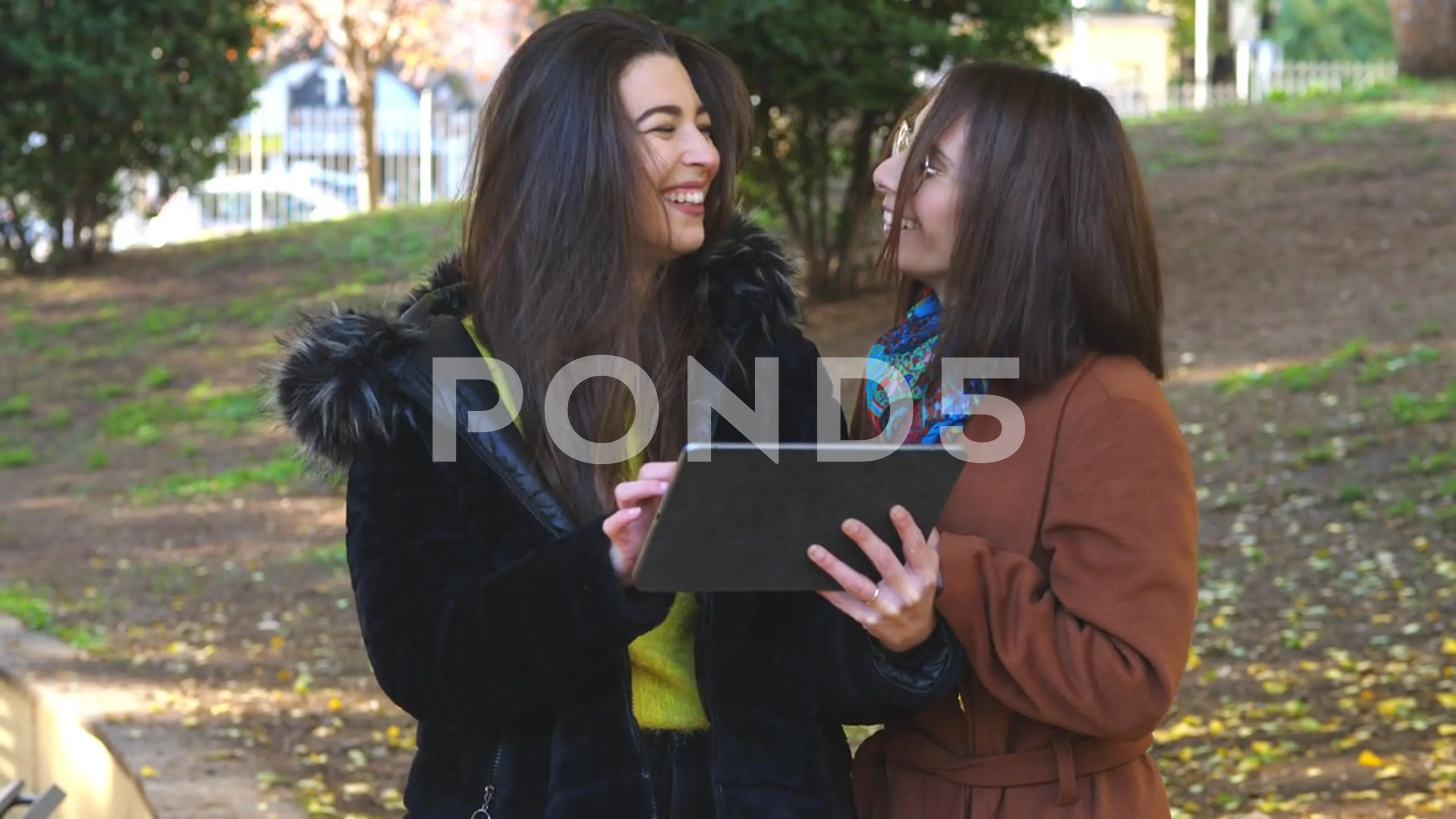 Two girlfriends watch a funny video on the tablet while laughing a lot  together