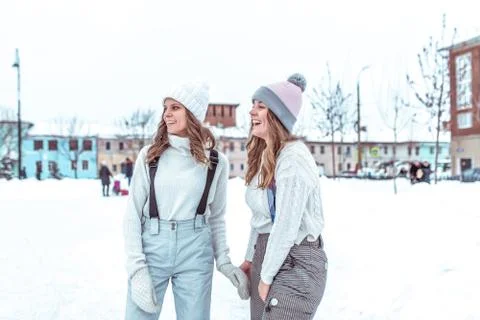 Two girlfriends in winter having fun outdoors, in warm winter clothes and hats Stock Photos
