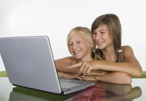 Two girls (10-11) using laptop, smiling Stock Photos