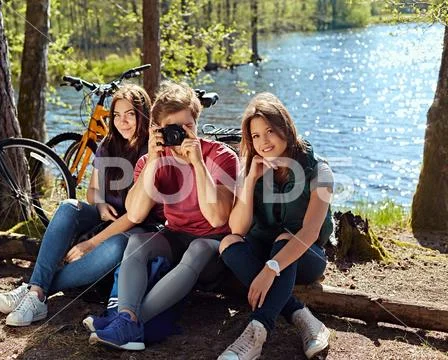 Two girls and a man taking photo pictures on the wild river coas Stock Photos