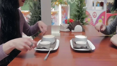 Two girls are drinking coffee and talking in a cafe. Video stock 77433818
