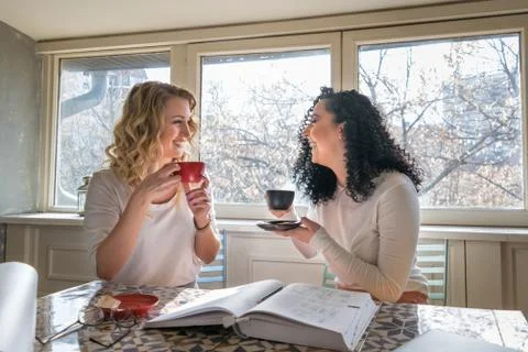 Two girls are drinking coffee and laughing in cafe Stock Photos