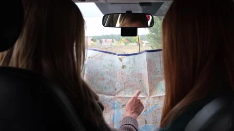 Two girls are reading a map. Friends are traveling by car in the forest. Stock Footage 254289599