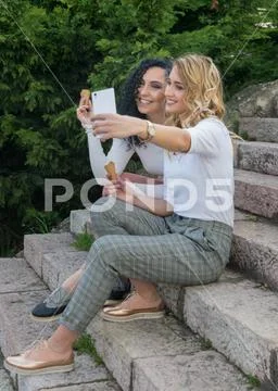 Two girls are taking selfies and eating ice cream Stock Photos