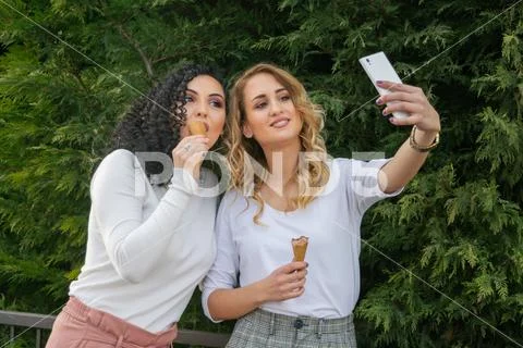 Two girls are taking selfies and eating ice cream Stock Photos