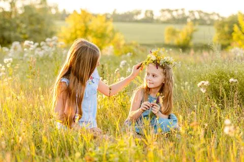 Two Girls Are Weaving Flower Crowns Stock Photos