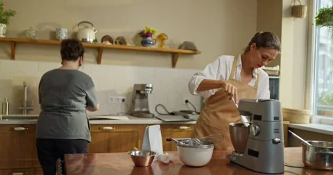 Two girls bakers work at the table while preparing desserts in a bakery. A girl Stockbeeldmateriaal 290040632