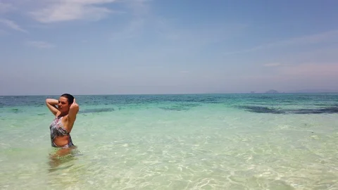 Two girls on the beach splashed water on a friend Stock Footage 129074880