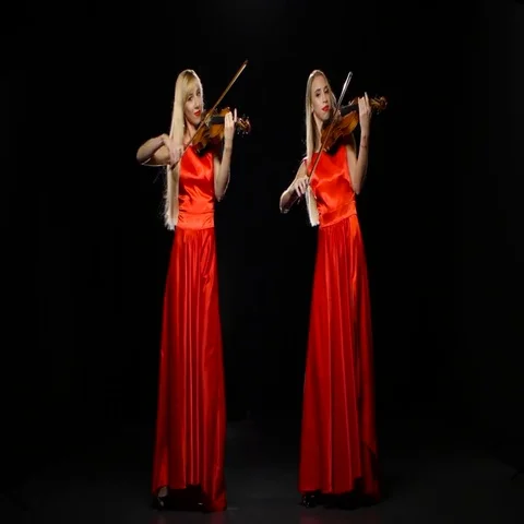 Two girls blonde playing the fiddle. Studio. Black background Stock Footage