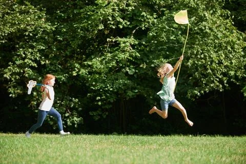 Two Girls Chasing Butterflies In Summer Field Stock Photos