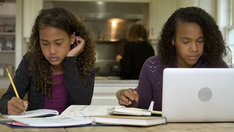 Two girls doing homework together in kitchen with mom helping. 스톡 동영상 88161386