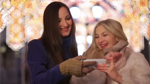 Two girls doing a selfie on the background of festive city lights. Stock Footage 59005875