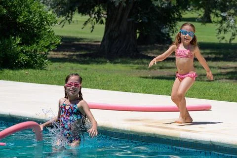 Two girls enjoy poolside fun on a sunny day Stock Photos