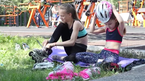 Two girls getting ready to roller skate on a sports ground Stock Footage 132890159