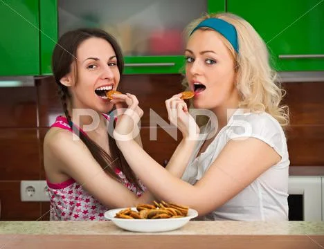 Two girls having fun with cookies in the kitchen Stock Photos